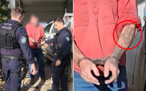 Two police officers cuff a man in a red shirt beside a white van, hands restrained in front of him.