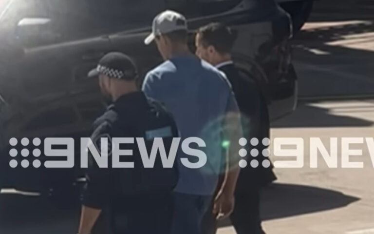 Three men walk beside a dark SUV on a sunny tarmac with a 9 NEWS watermark overlaid on the image.
