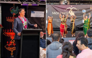 Man speaking at a podium with a garland, on a decorated stage during a multicultural festival.