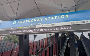 Blue Footscray Station sign above escalators leading to Platforms 1–5; a digital banner announces Free Travel Until Sunday 31st May across Victoria.
