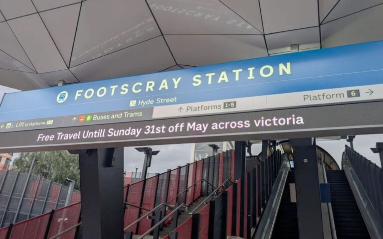 Blue Footscray Station sign above escalators leading to Platforms 1–5; a digital banner announces Free Travel Until Sunday 31st May across Victoria.