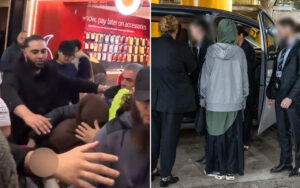 Crowd surrounding a person in a hoodie on a city street at night, with a phone accessory shop sign visible in the background to suggest a busy storefront area.