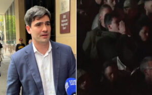 Man in a blue suit being interviewed outside Melbourne Magistrates' Court; blue news microphone visible in foreground