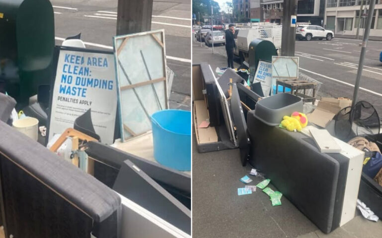 Pile of discarded furniture and debris on a city sidewalk with a 'Keep Area Clean: No Dumping Waste' sign nearby, indicating illegal dumping.