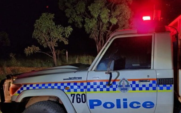 Police vehicle at night with red emergency light on, white SUV marked with blue 'Police' text and checkered stripe.