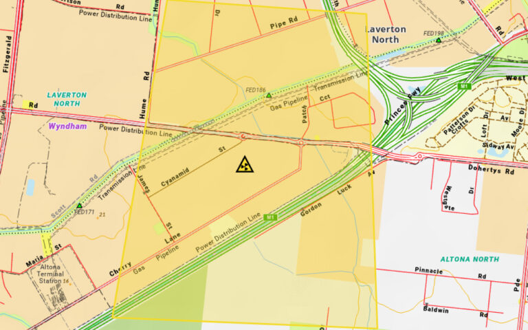 Map of an urban area showing a major highway interchange (M1) with multiple green on-ramps, a large yellow polygon area indicating a restricted/zone, and a safety warning triangle symbol near a road junction.