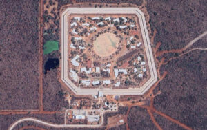 Aerial view of a circular walled compound with concentric rings and many small buildings inside.