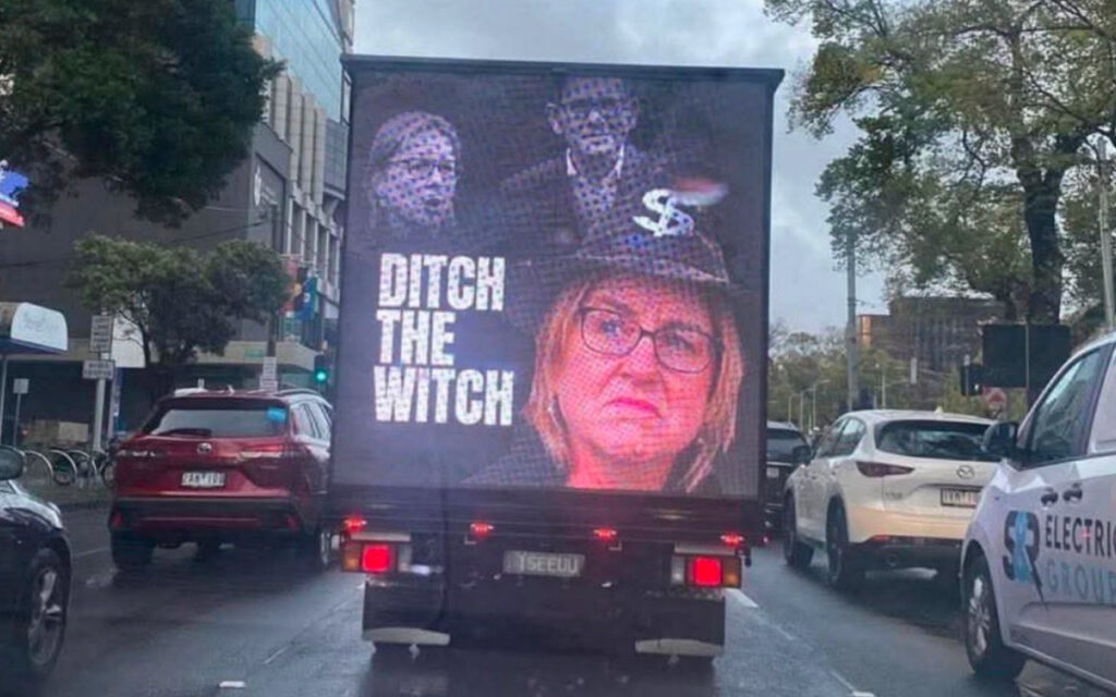 Truck with a political ad: 'DITCH THE WITCH' and a woman’s portrait on the back, on a city street.