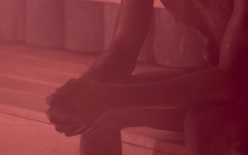 Close-up of a person’s feet in platform sandals resting on a wooden floor with a red tint.