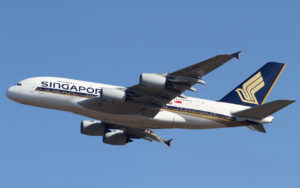 Singapore Airlines Airbus A380 in white and blue livery with four engines, flying left to right against a clear blue sky.