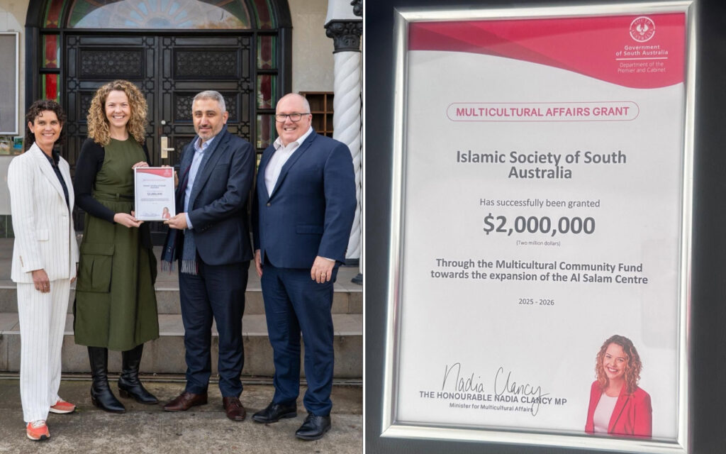 Four people stand on steps; a woman in a green dress holds a grant certificate as others smile and pose for the photo outside a building with ornate doors. Left panel of a two-part image.