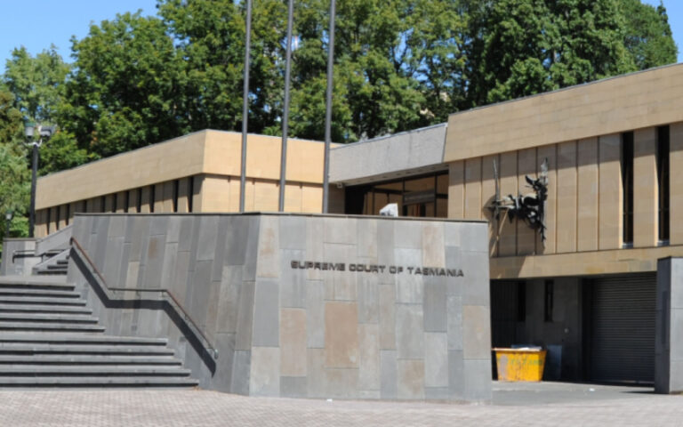 Exterior view of the Supreme Court of Tasmania with a stepped staircase and a grey stone wall leading to the entrance.