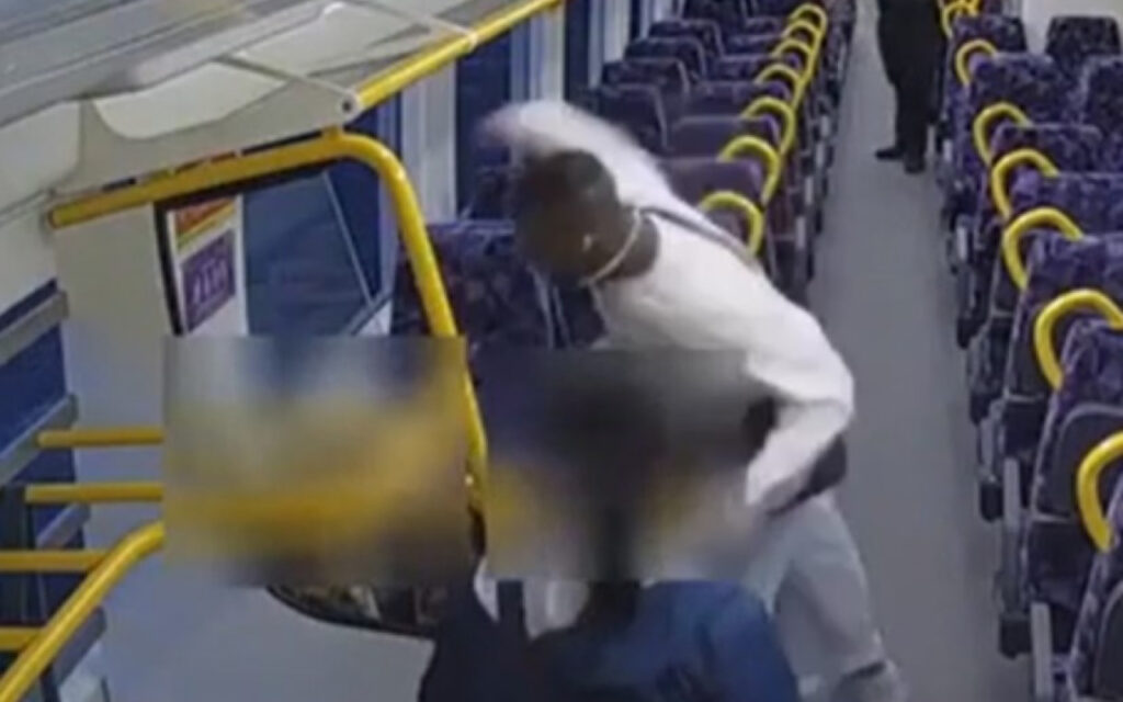 Two passengers on a bus appear to be involved in a physical altercation near the front, with one person in white clothing reaching toward the other and motion blurred.