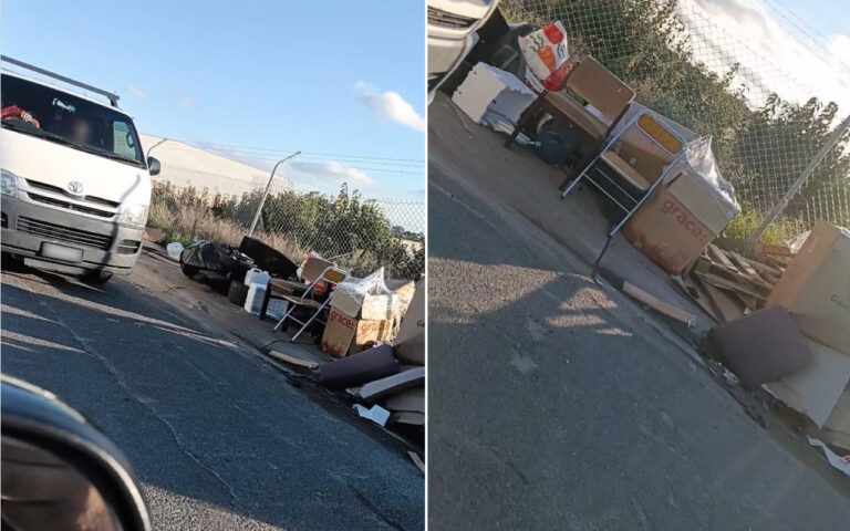 White van on a sunlit street with debris and cardboard boxes scattered along the curb near a chain-link fence on the side of the road.