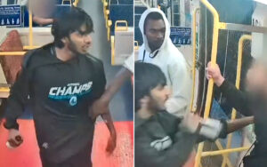 Two men on a bus appear to be in a confrontation: one in a dark jacket on the left, another in a white hoodie on the right, with a person grabbing the left man's arm.