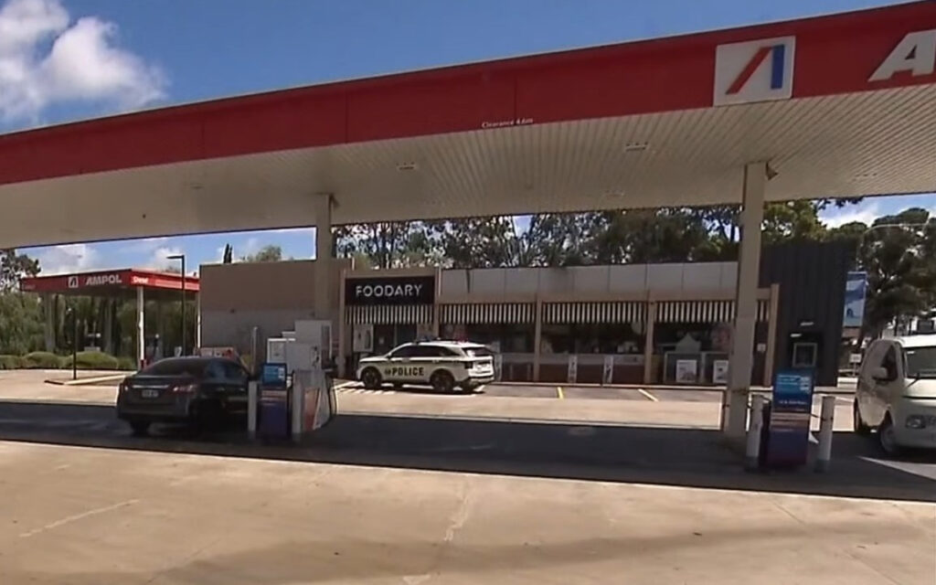 Police SUV parked at a gas station under a red canopy near a convenience store labeled FOODARY.