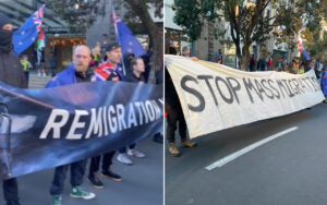 Protest on a city street with people holding a long white banner that reads ‘STOP MASS MIGRATION’ and waving flags. Several participants wear masks and warm clothing.