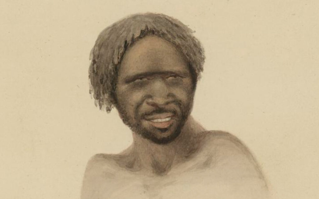 Portrait of a shirtless man with dreadlocks and a short beard, smiling with squinting eyes.