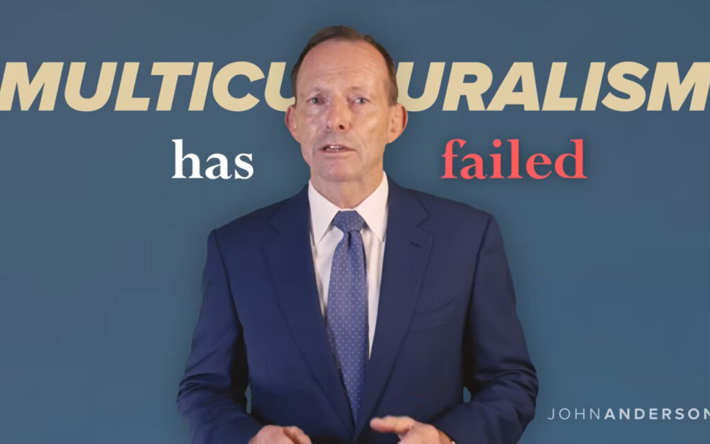 Presenter in a navy suit speaks in front of a blue backdrop with the bold text 'MULTICULTURALISM has failed'.