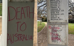 Two-panel memorial vandalized with red spray paint: left panel reads 'DEATH TO AUSTRALIA'; right panel lists names with red markings over the plaques.