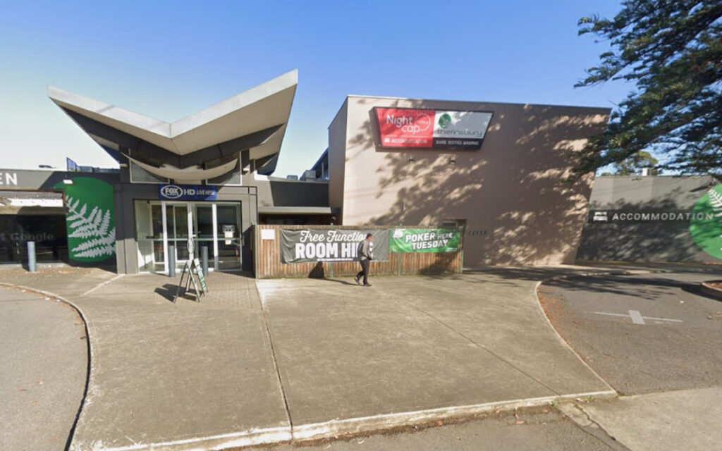 Modern venue entrance with a V-shaped roof and banners advertising room hire and poker night.
