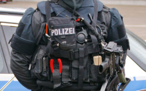 Back view of a police officer in a tactical vest and equipment, with POLIZEI label visible on the vest.