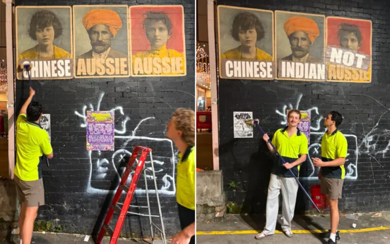 Two workers in bright shirts paint graffiti on a black brick wall beneath large vintage portrait posters; a red ladder leans against the wall.