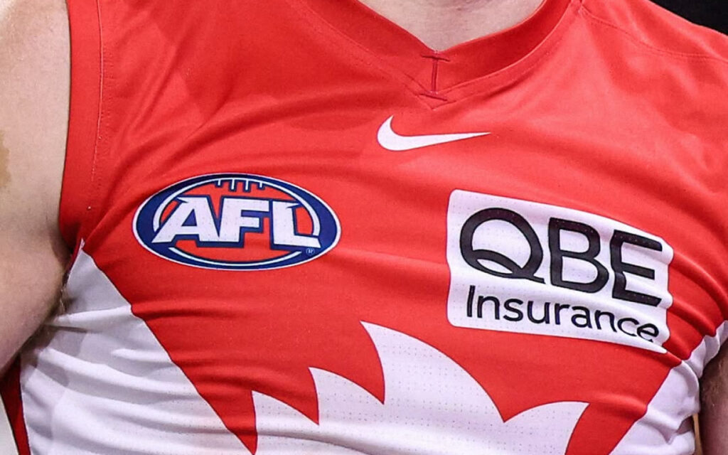 Close-up of a red Australian football league jersey displaying AFL and QBE Insurance logos, plus a white Nike swoosh and white design on the side.