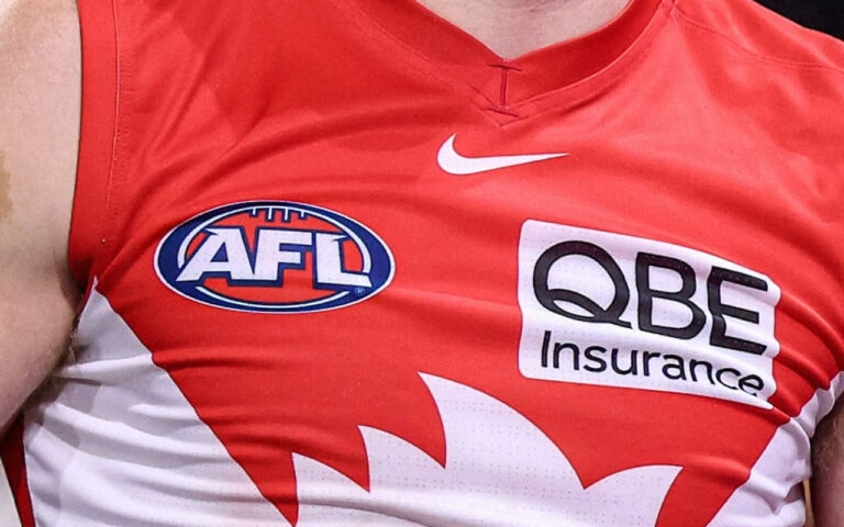 Close-up of a red Australian football league jersey displaying AFL and QBE Insurance logos, plus a white Nike swoosh and white design on the side.